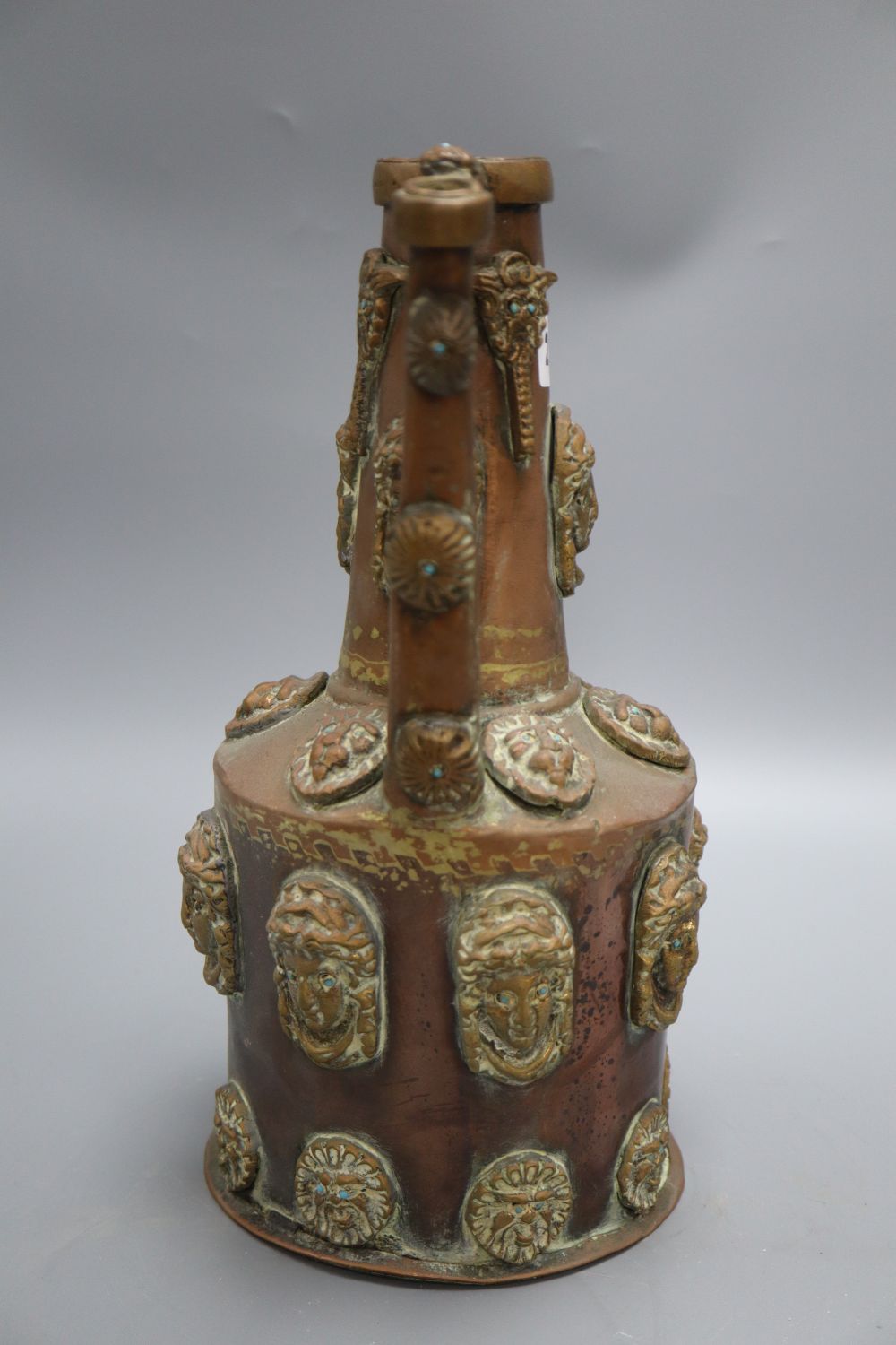 A Middle Eastern copper pot, decorated with classical ladies and lions faces with turquoise beaded eyes, height 32cm